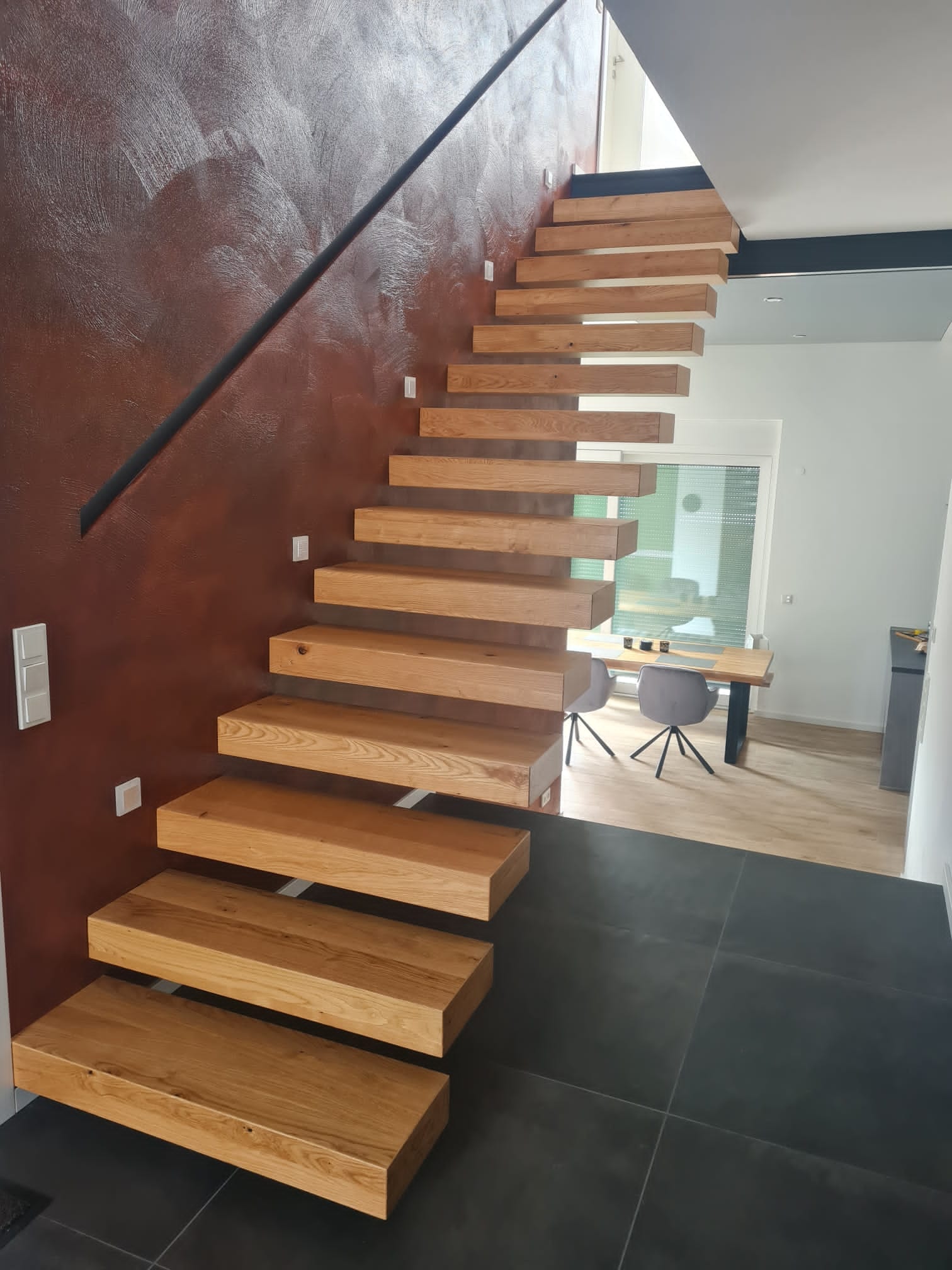 Kragarmtreppe Eiche mit Glasgelaender dunkler BodenSchwebende Holzkragarmtreppe mit Glasgelaender – maßgefertigt von AN Treppenbau