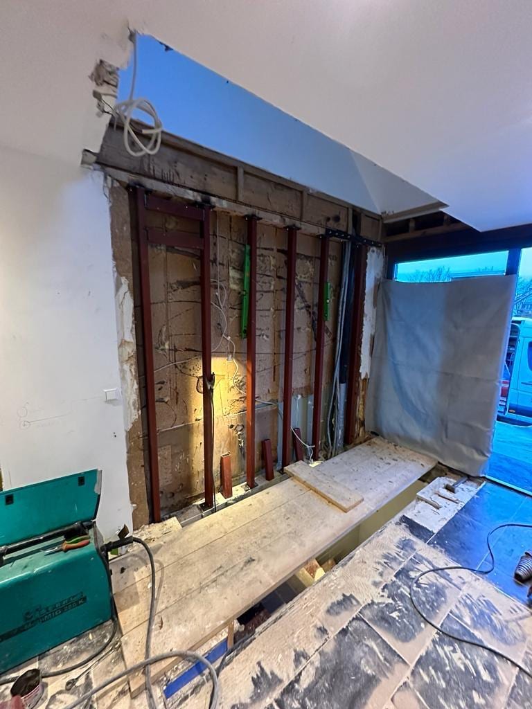 Geöffnete Holzständerwand mit eingebautem Stahlrahmen für die Kragarmtreppe, Dampfbremse teilweise zurückgeschlagen – AN Treppenbau
