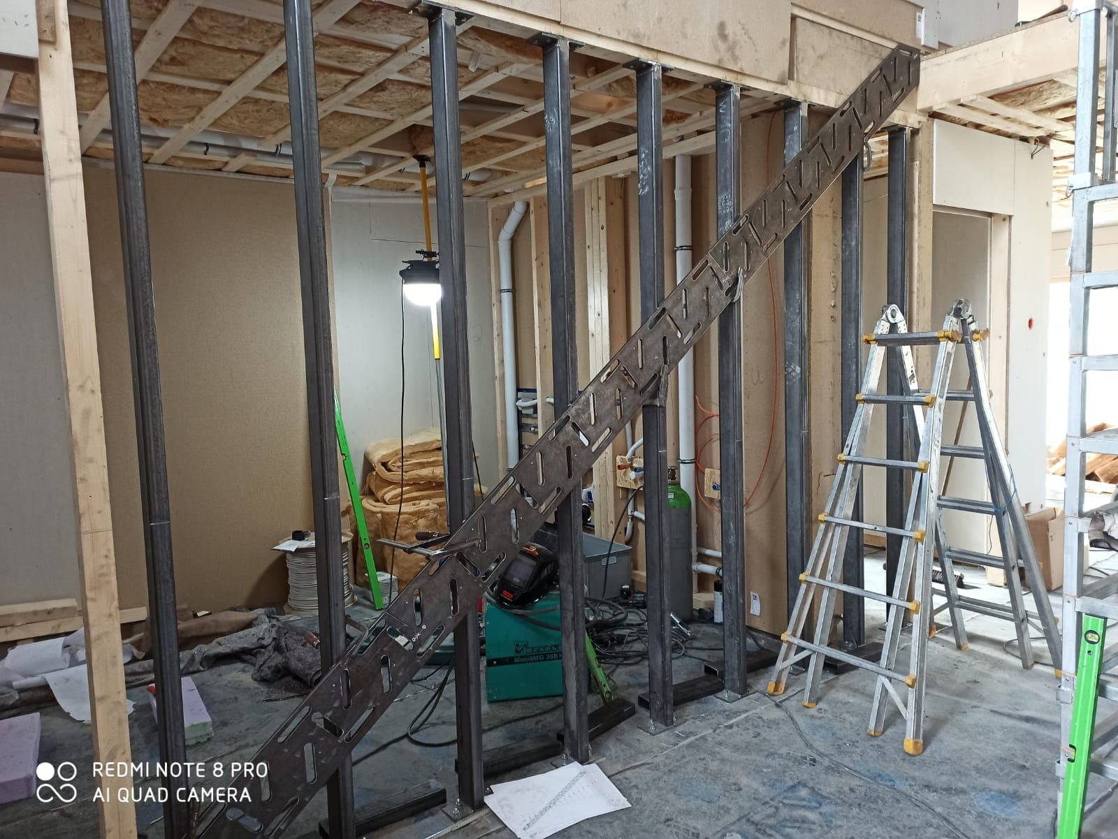 Stahlrahmen für die Kragarmtreppe zwischen den Holzständern, Montage im Rohbau mit Leiter – AN Treppenbau