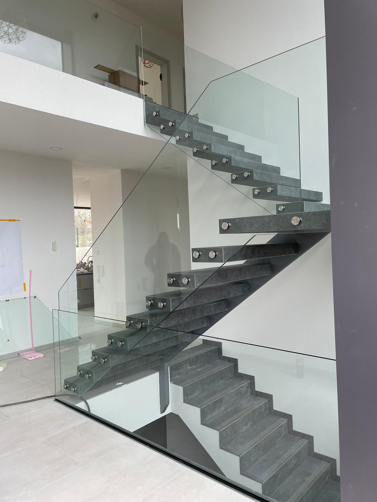 Kragarmtreppe mit grauen Stufen in Steinoptik und Ganzglasgeländer, Gesamtansicht des kompletten Laufs – AN Treppenbau