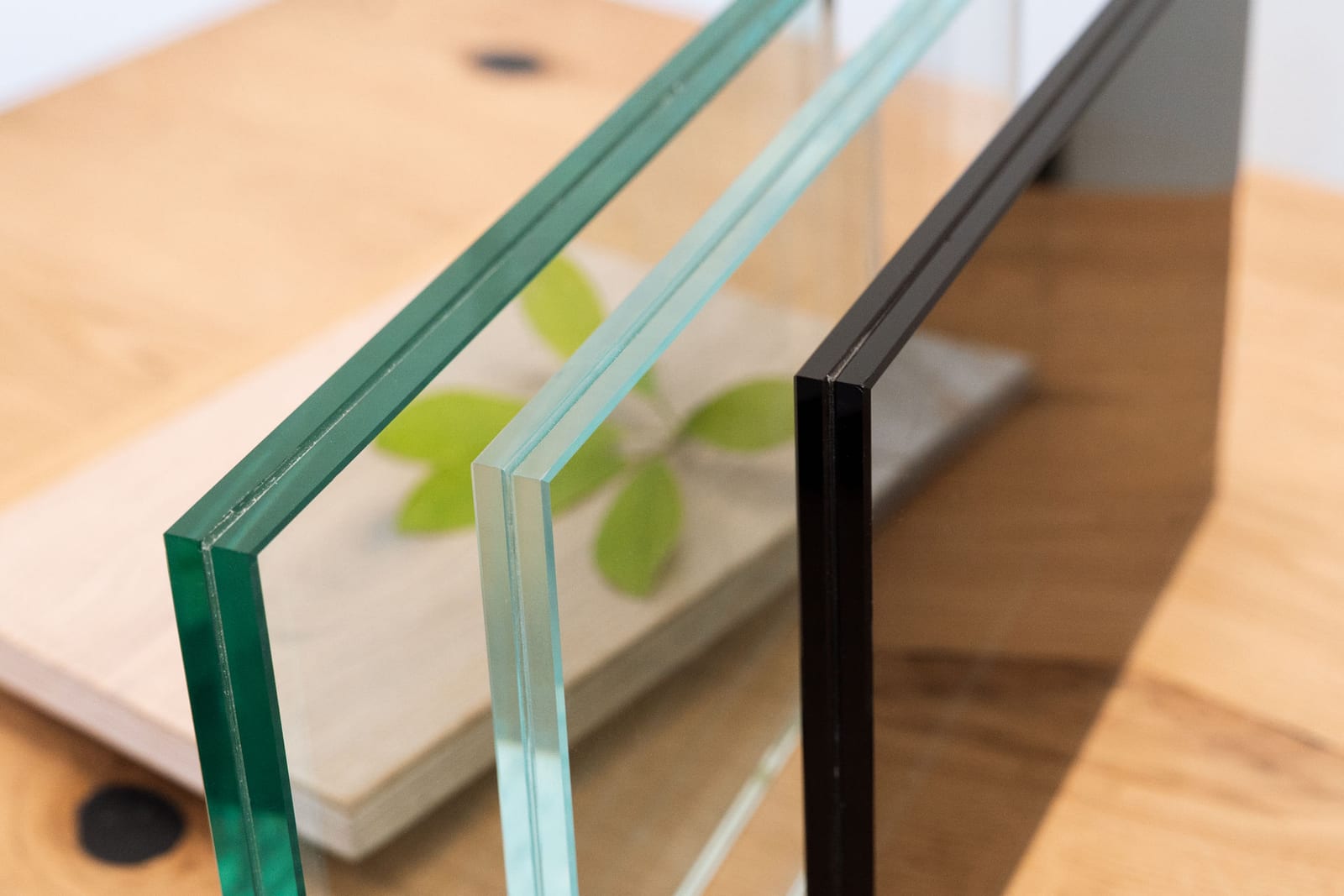 Drei Glasmuster im Vergleich: grünliche Kante von Floatglas, fast farblose Kante von Weißglas, schwarz getöntes Glas