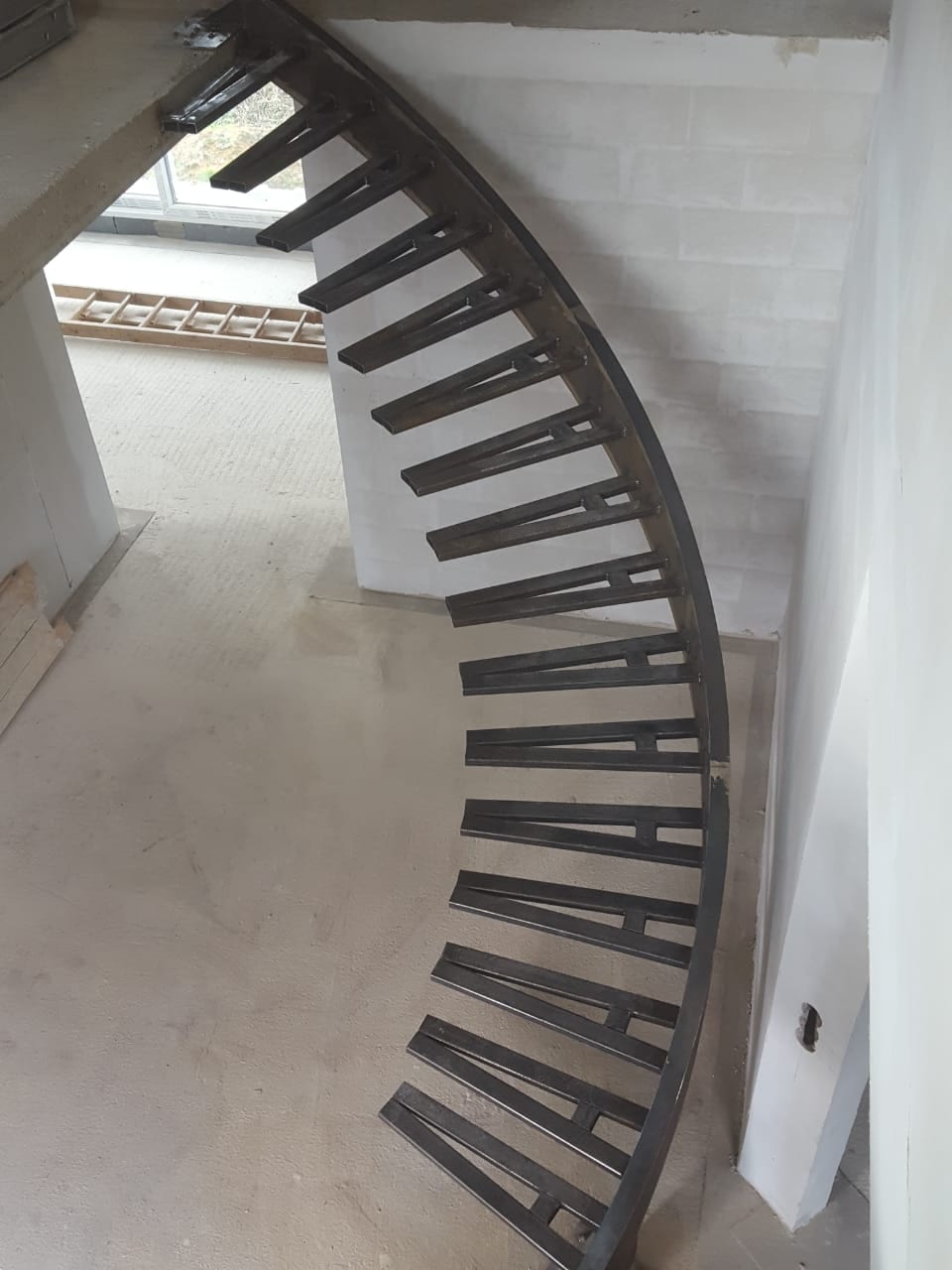 Gebogene Kragarmtreppe im Rohbau, Blick von oben in das Treppenauge – AN Treppenbau