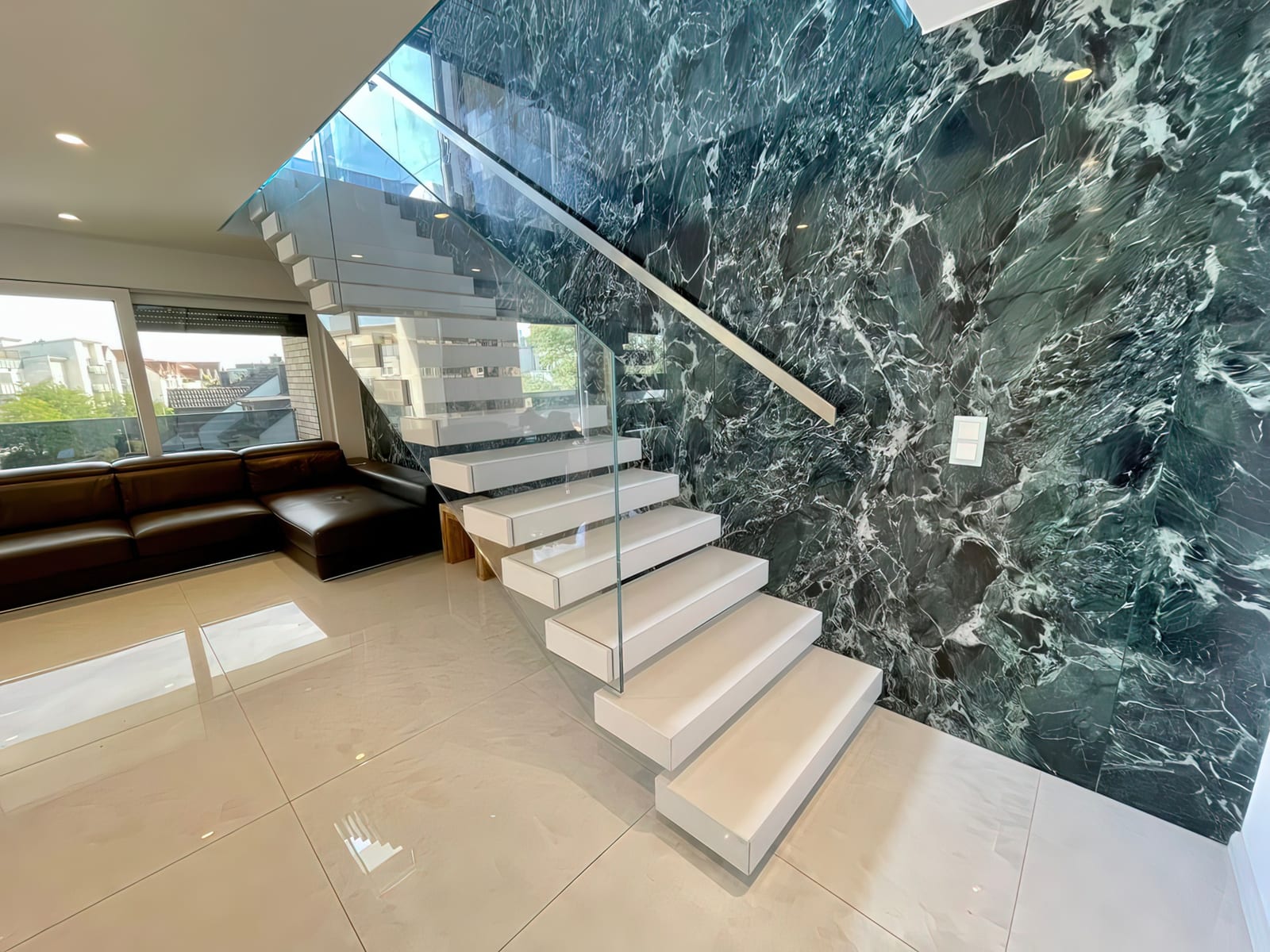 Kragarmtreppe mit weißen Blockstufen vor dunkelgrün gemaserter Wandverkleidung, Ganzglasgeländer – AN Treppenbau