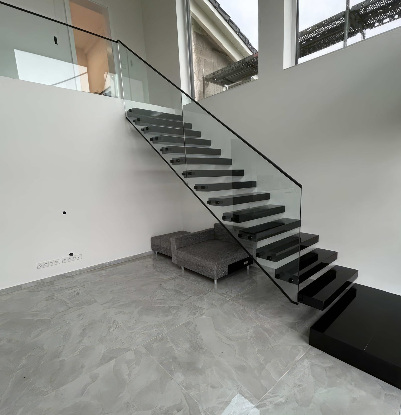 Kragarmtreppe mit dunklen, glänzenden Stufen im Gesamtblick, Ganzglasgeländer entlang des Laufs – AN Treppenbau