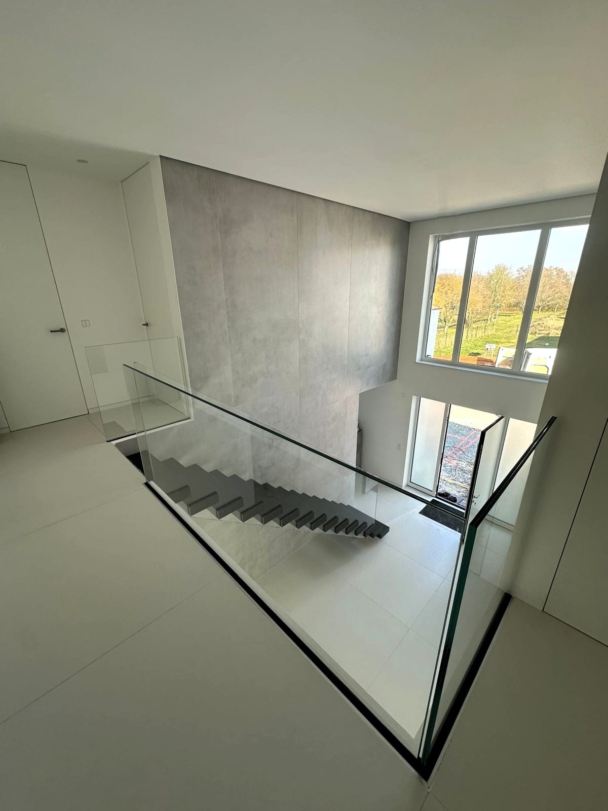 Blick von der oberen Etage auf die freitragende Treppe, Glasgeländer rund um die Deckenöffnung – AN Treppenbau
