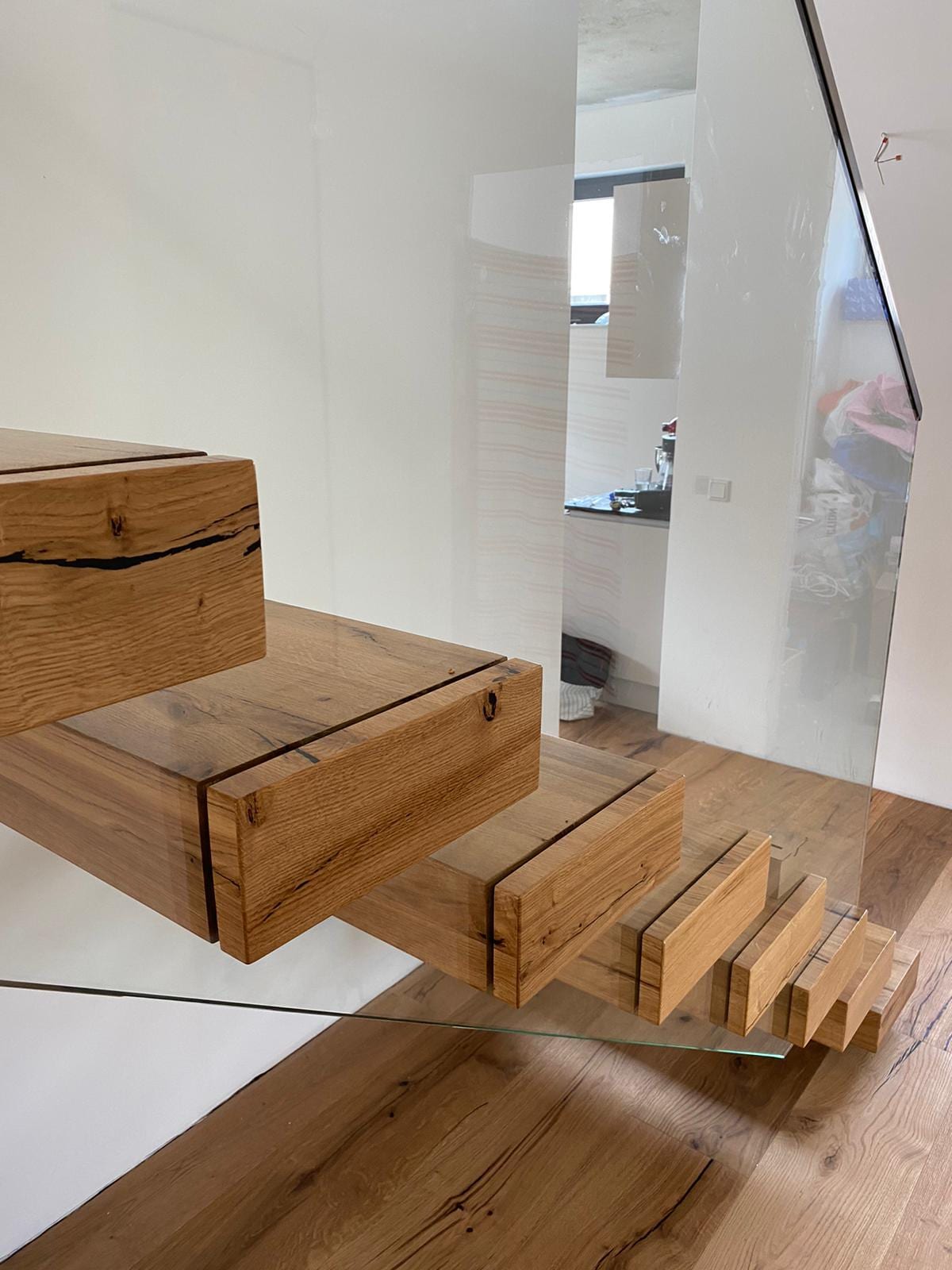 Treppenauge einer Kragarmtreppe aus Eiche: gewendelte Stufen mit Glasgeländer, Blick von oben