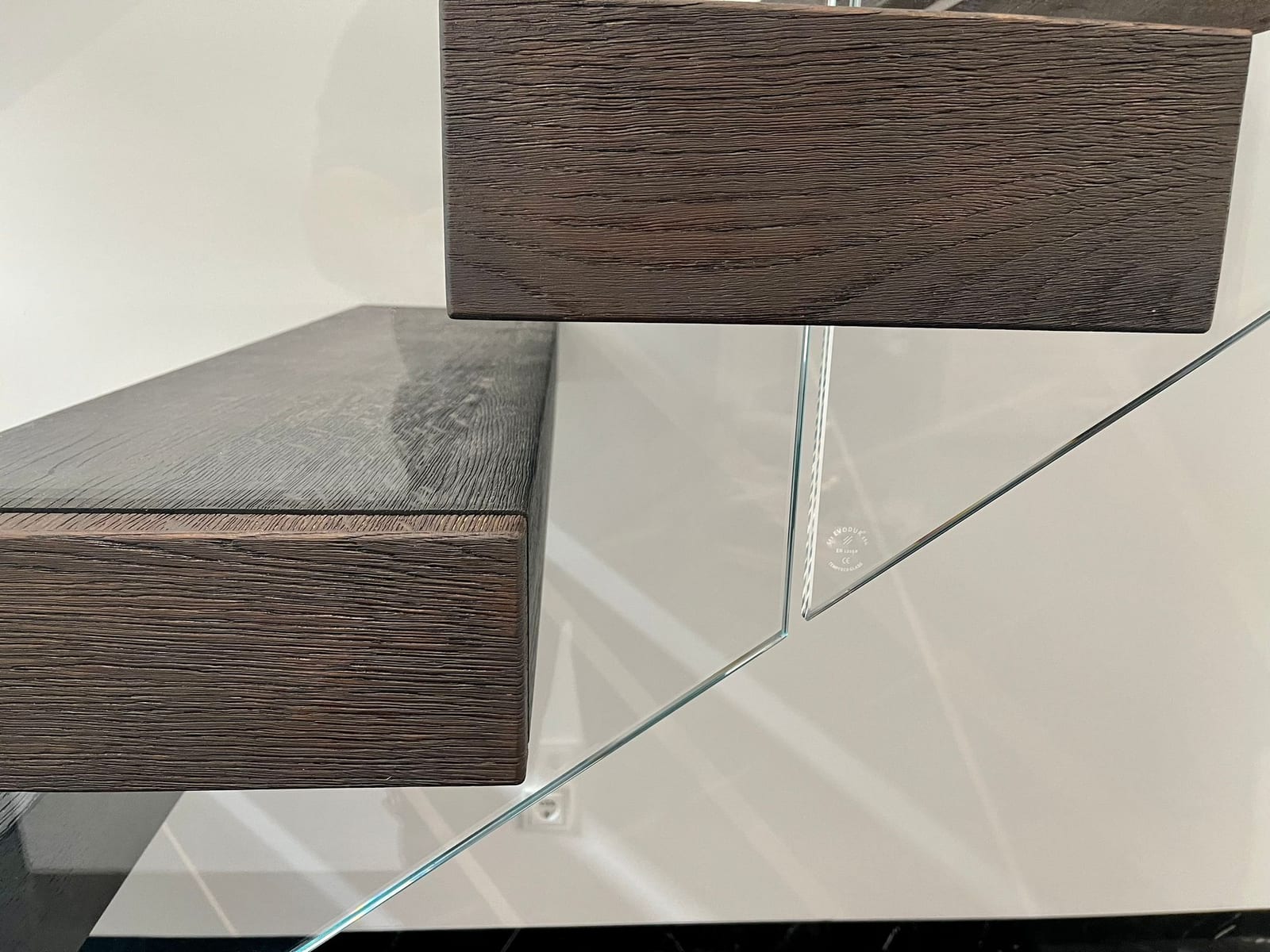 Stufe aus geräucherter Eiche mit Glasgeländer im Detail, Kante und Glasanschluss