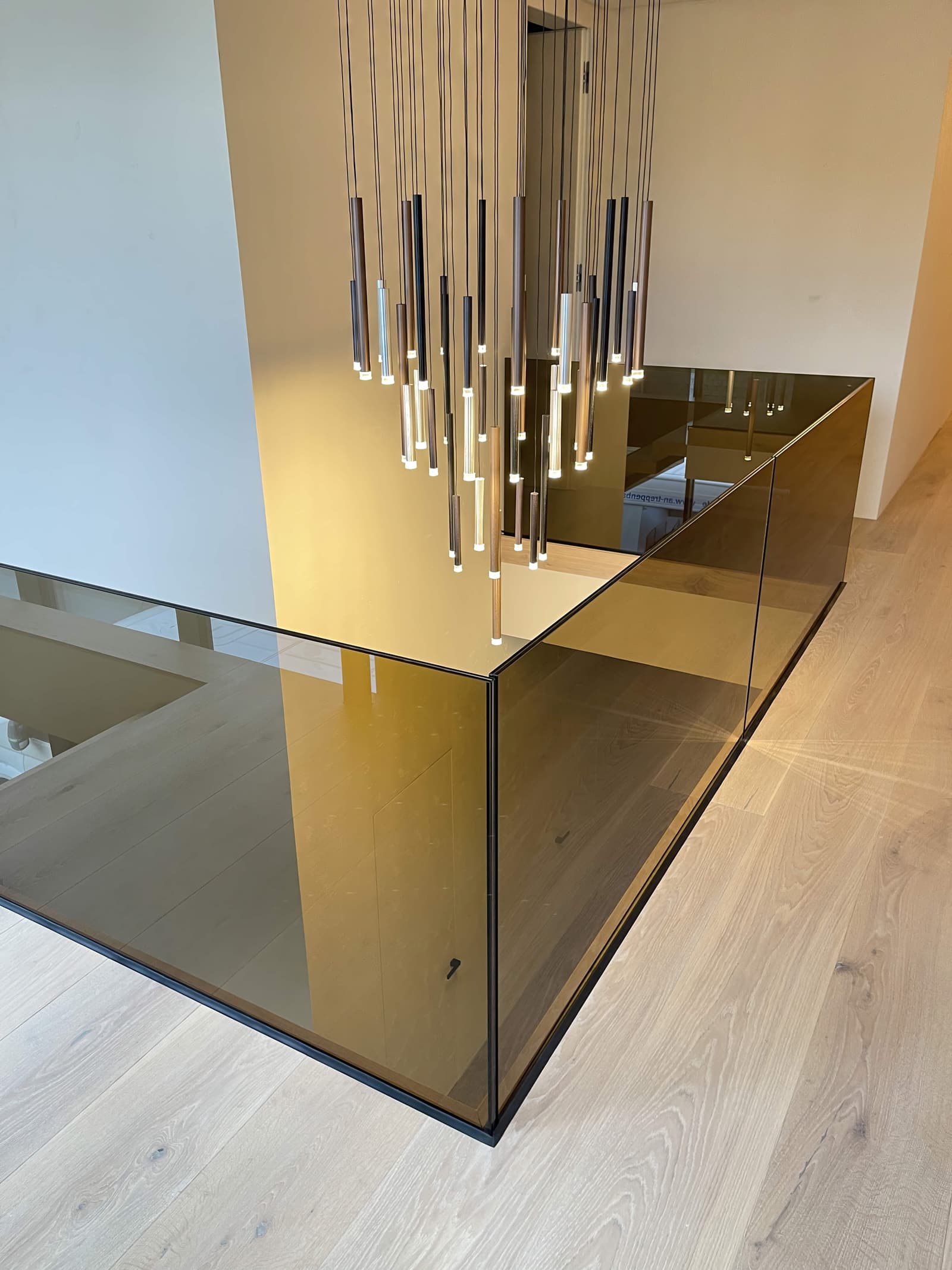 Rahmenloses Ganzglasgeländer in Bronzeglas an einer Galerie mit hellem Holzboden