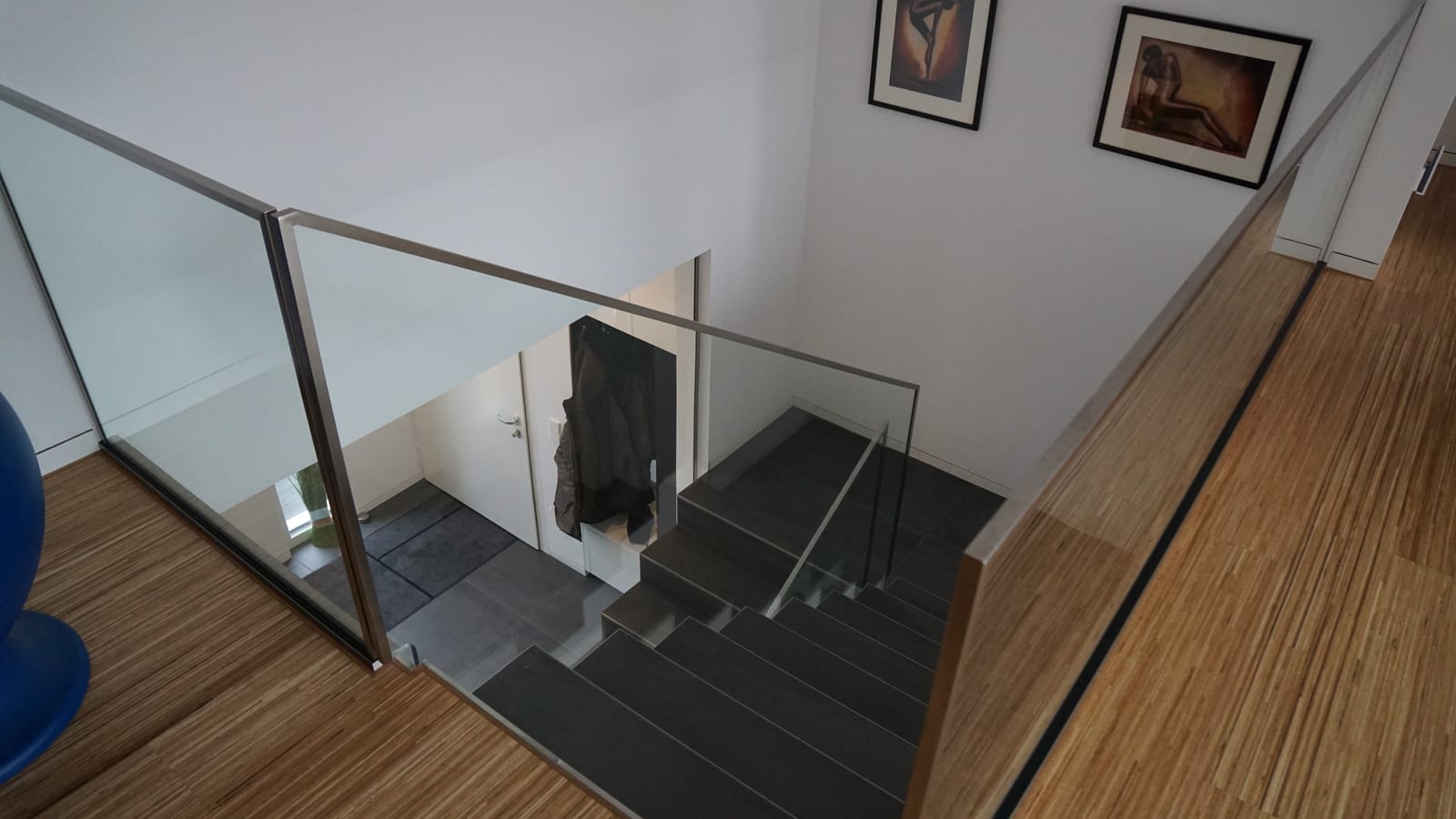 Galerie mit Glasbrüstung und Holzhandlauf über einer Kragarmtreppe mit dunklen Stufen