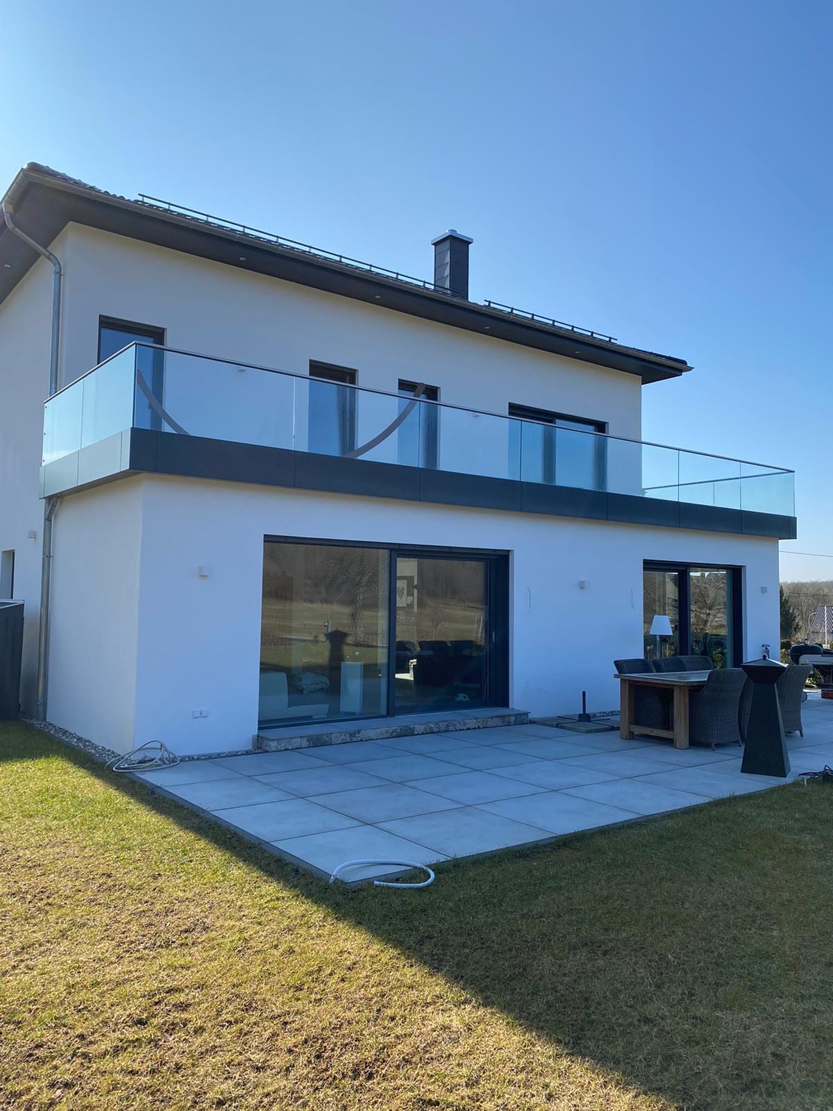 Wohnhaus mit Ganzglasgeländer am Balkon über der Terrasse