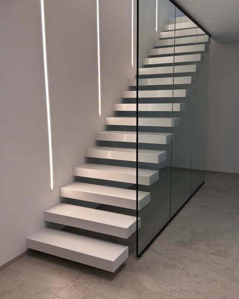 Weiße Kragarmtreppe mit Glasgeländer und LED-Lichtlinie an der Wand