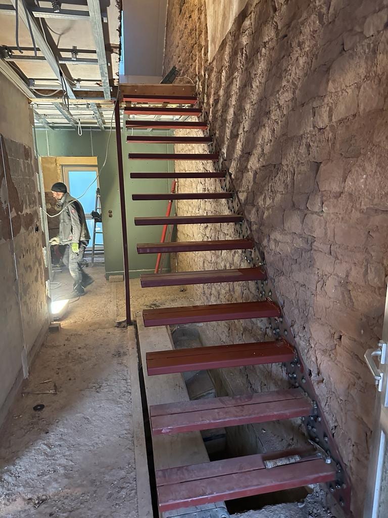 Treppenaustausch im Altbau: Stahl-Unterkonstruktion der Kragarmtreppe an einer Bruchsteinwand vor dem Verputzen