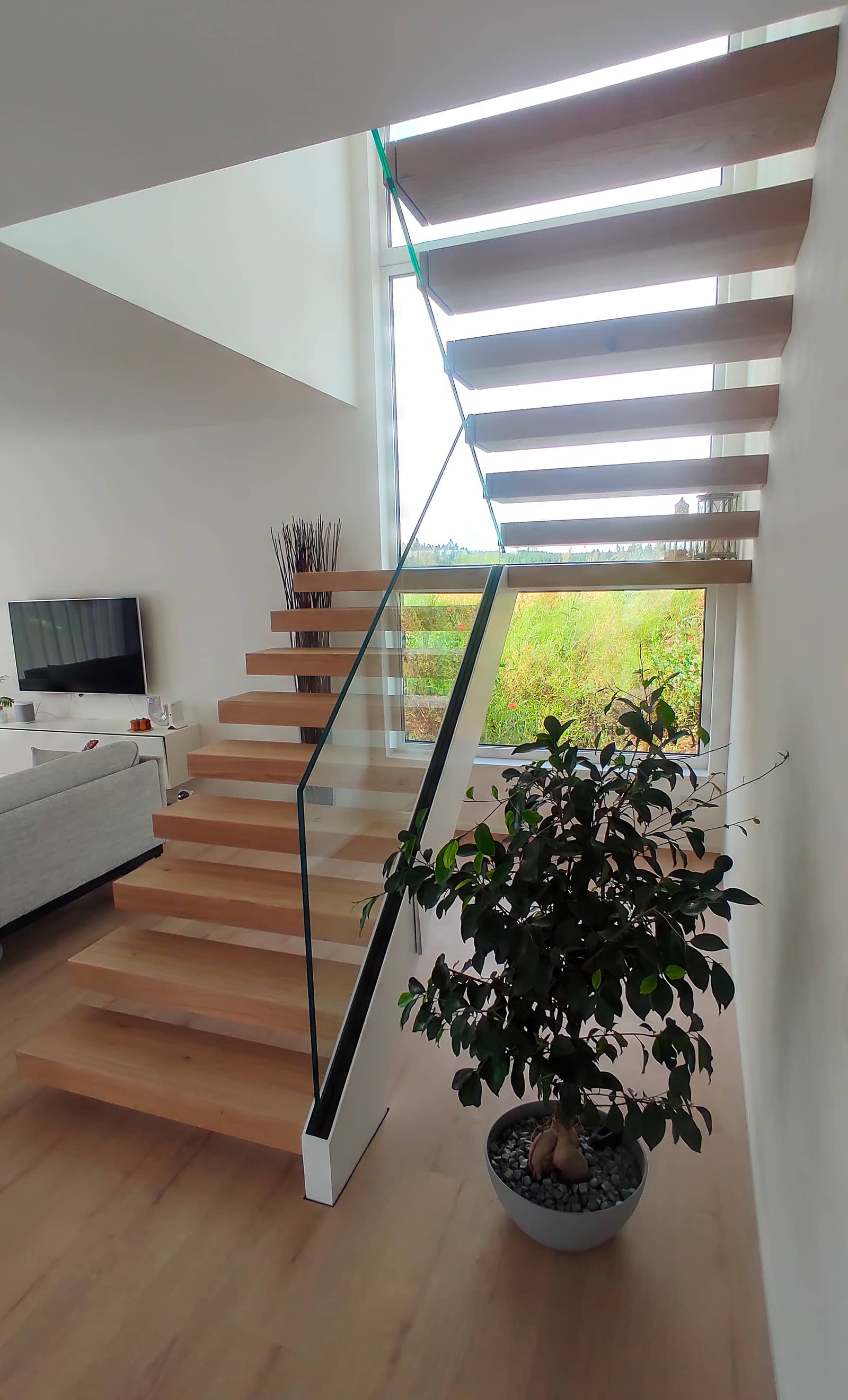 Kragarmtreppe aus Eiche mit Glasgeländer im Wohnraum, Blick von der Galerie hinab