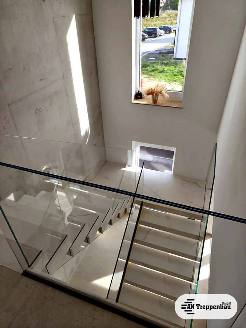 Klarglas-Geländer an der Galerie mit schwarzem Profil auf der Oberkante, Blick von oben auf die Treppe