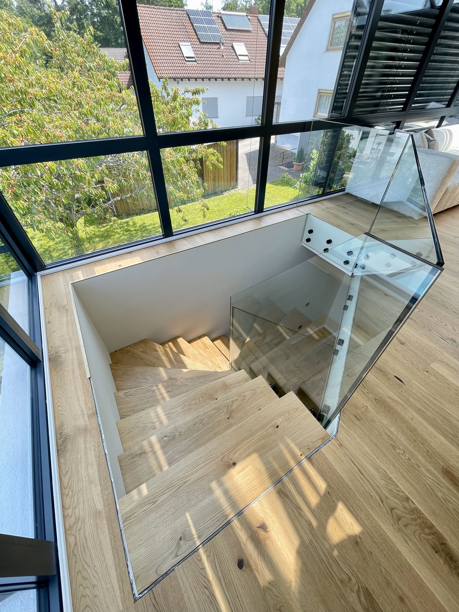 Blick von oben auf die neue Kragarmtreppe im Wohnhaus mit Glasfront – AN Treppenbau