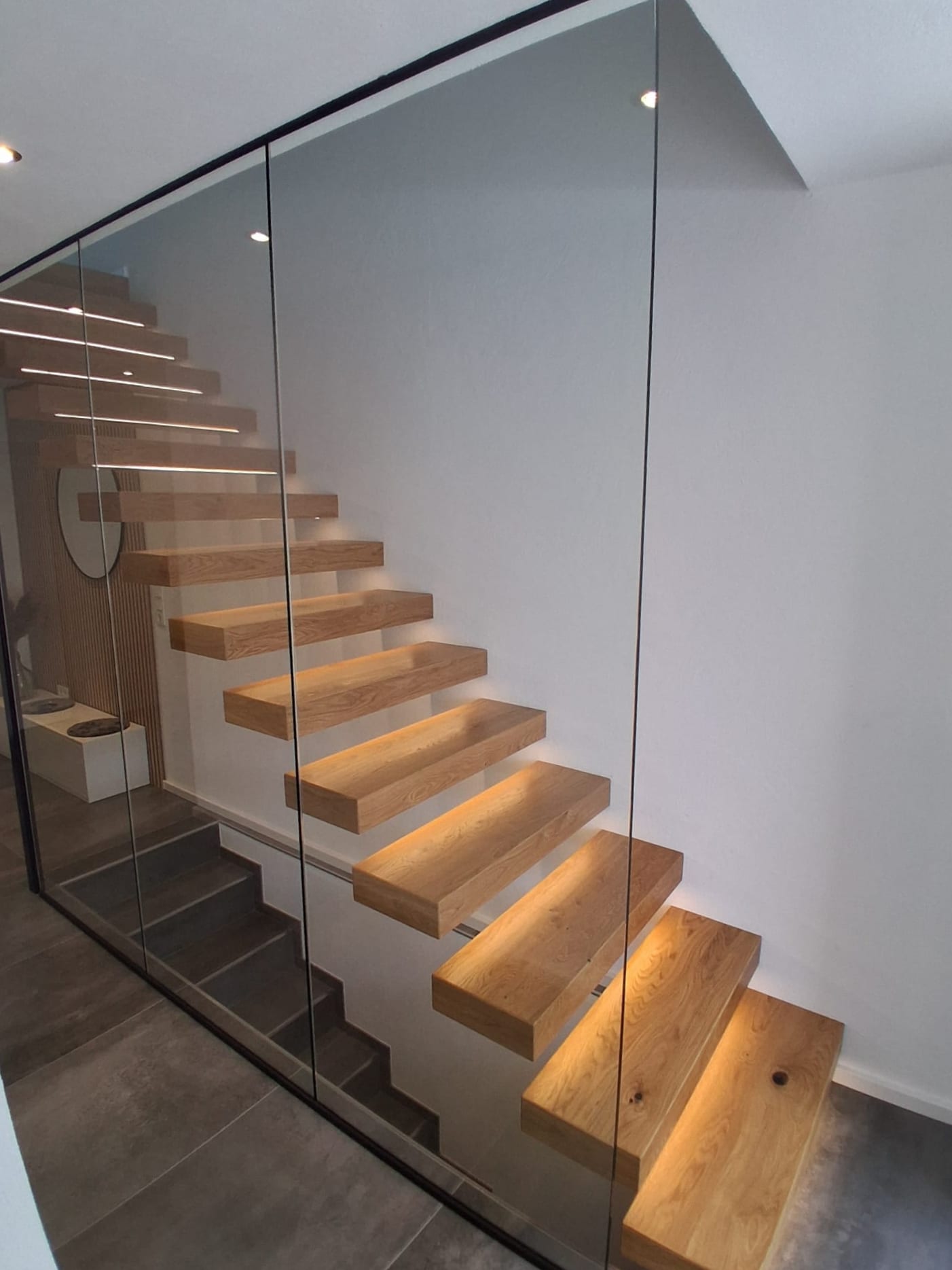 Kragarmtreppe in Eiche hinter einer Ganzglaswand – AN Treppenbau