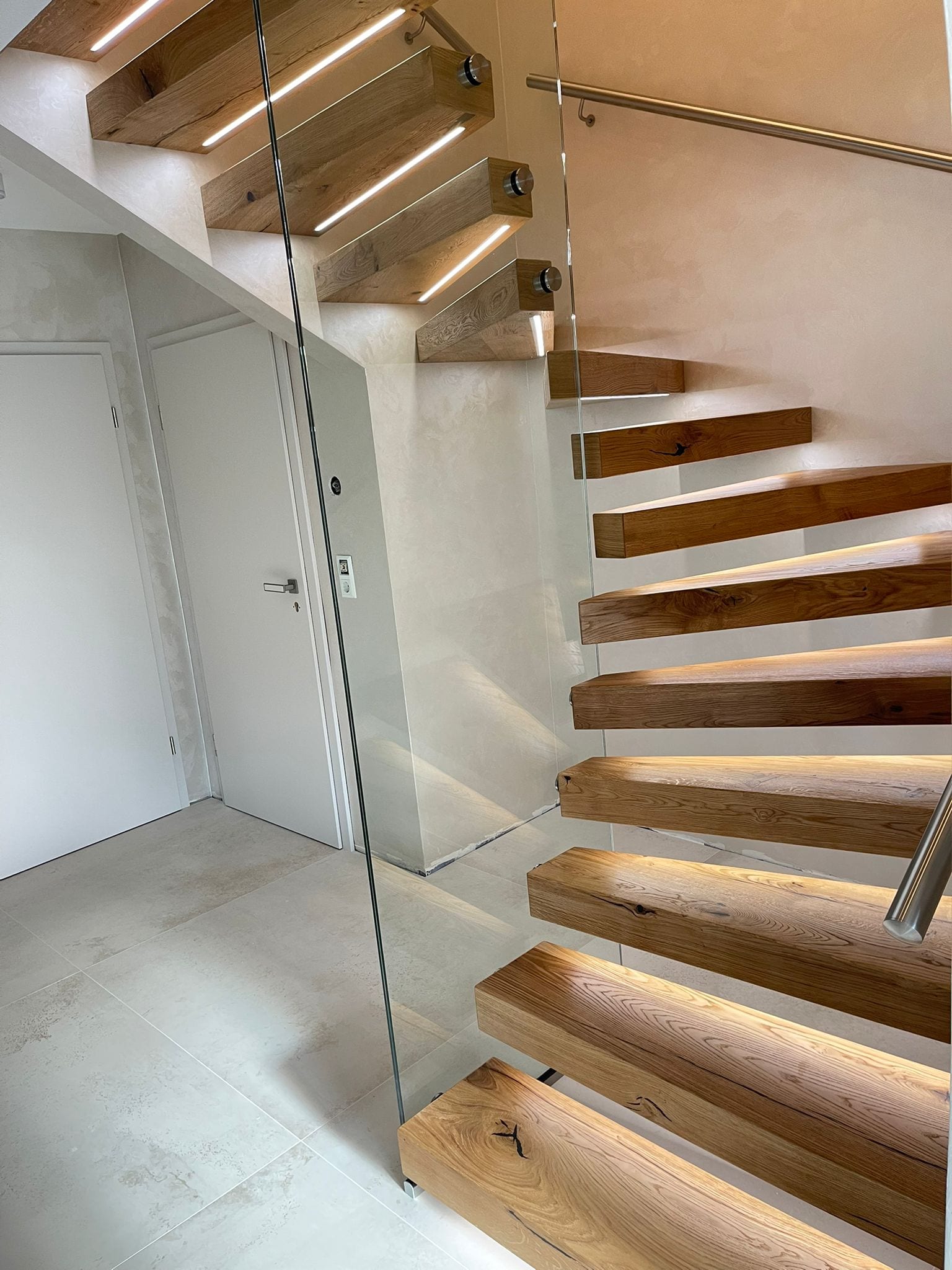 Kragarmtreppe in Eiche mit Glasgeländer und Wandhandlauf, Blick von unten – AN Treppenbau