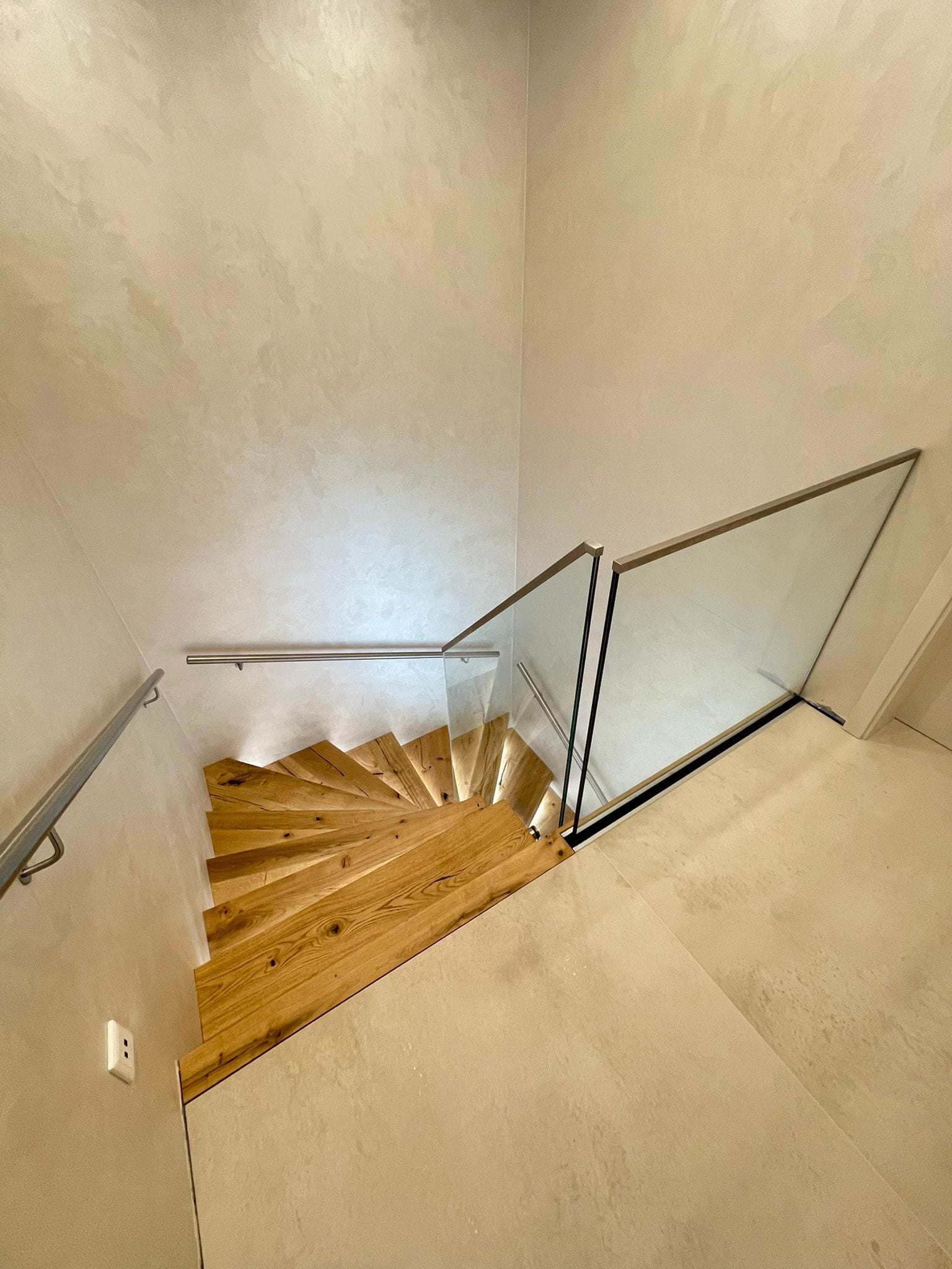 Gewendelte Treppe mit Glasgeländer nach dem Umbau, Blick von oben – AN Treppenbau