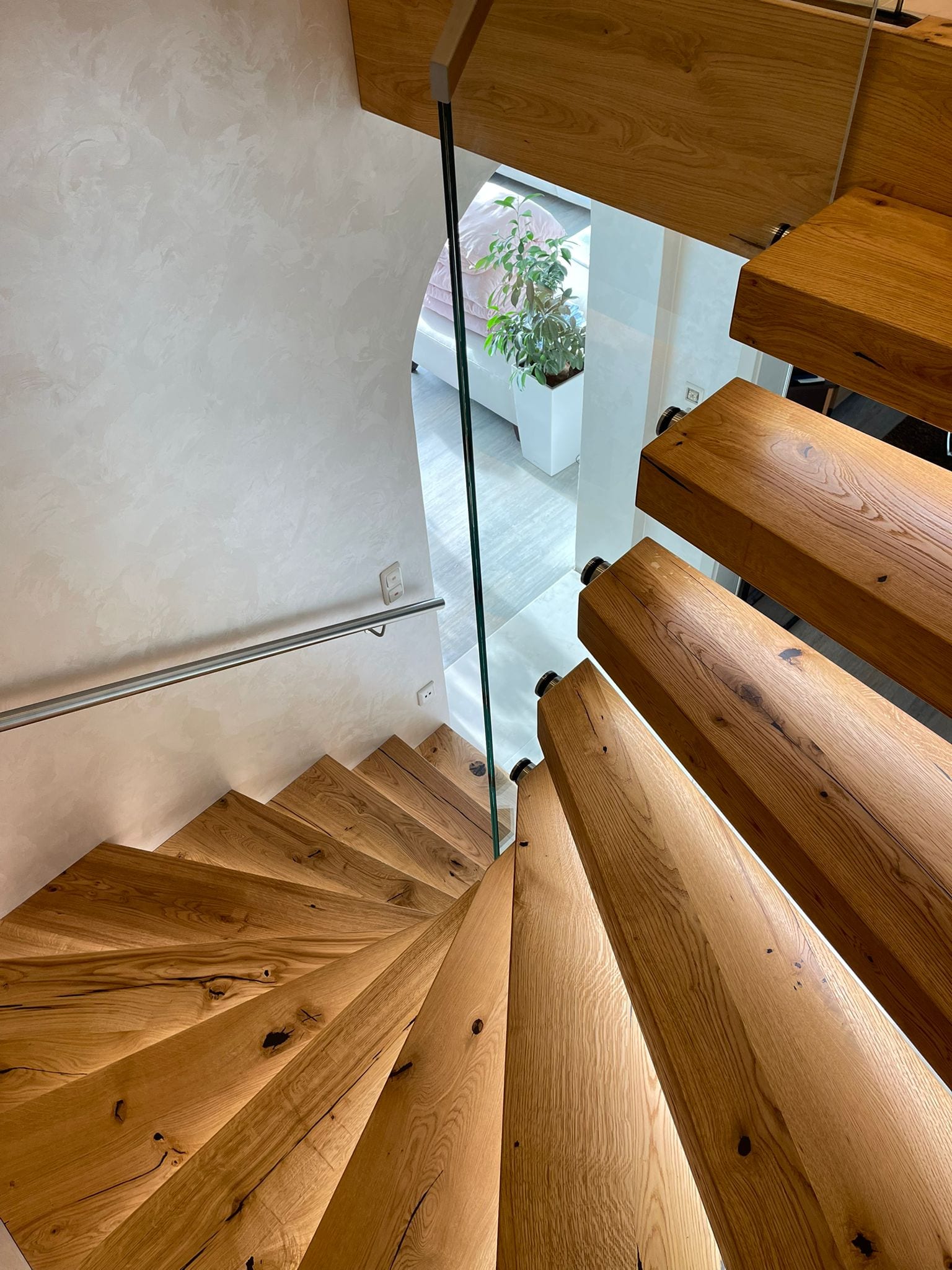 Gewendelte Kragarmtreppe in Eiche mit Glasgeländer, Blick von oben – AN Treppenbau