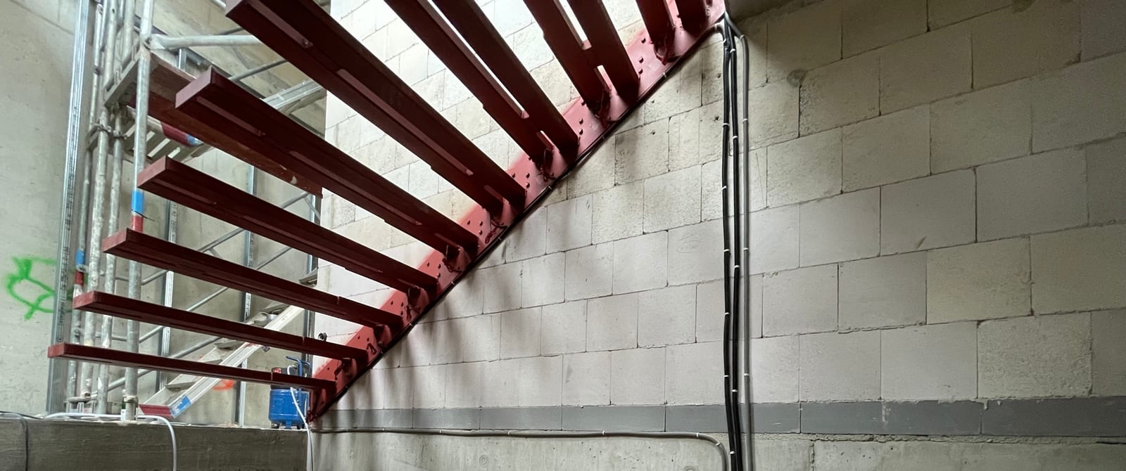 Rot grundierte Kragarme im Rohbau, Leerrohre für die Stufenbeleuchtung liegen bereit – AN Treppenbau