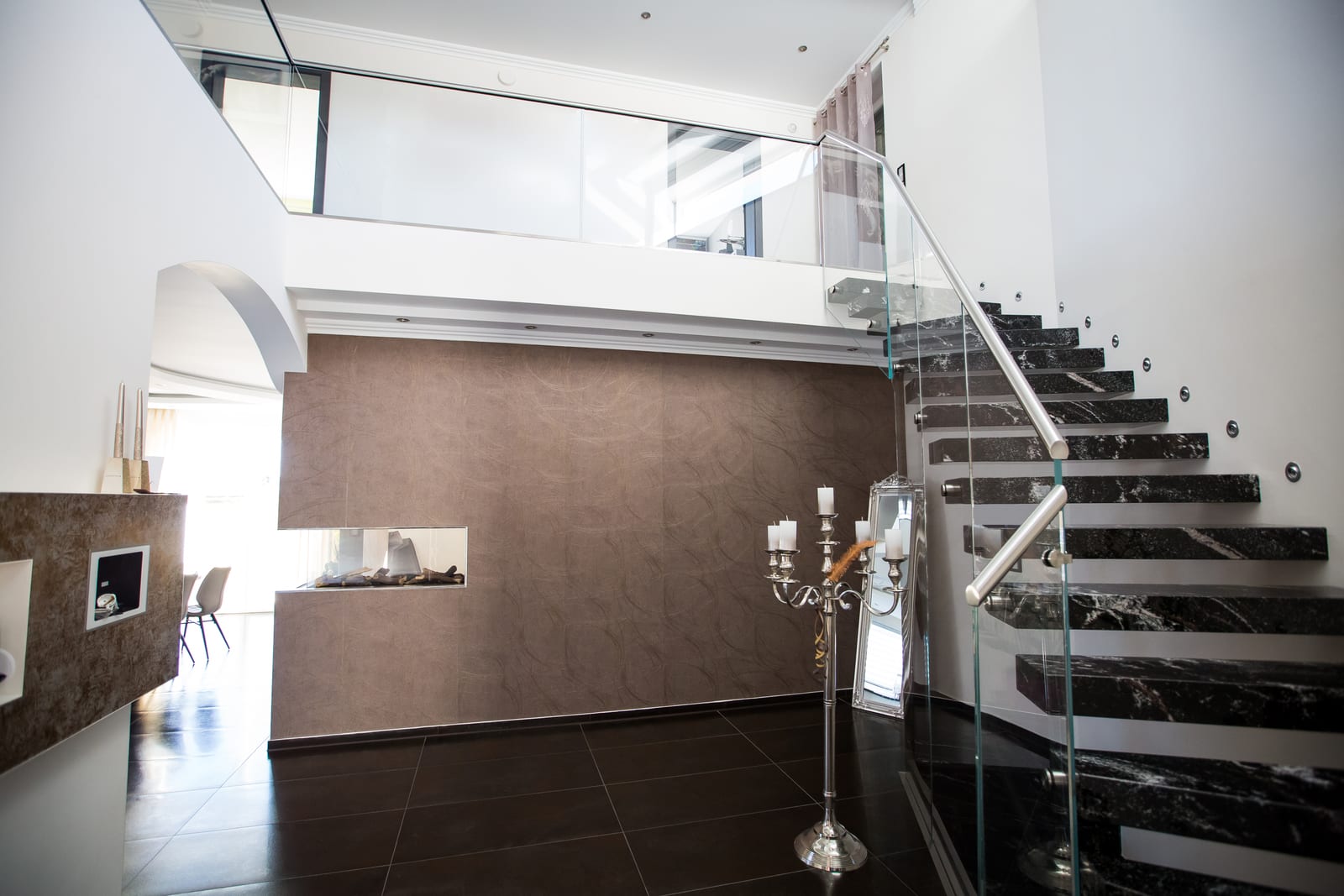 Kragarmtreppe mit dunklen Marmorstufen und Glasgeländer im Wohnraum – AN Treppenbau